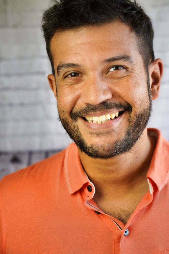 Jason Delgado smiling in an orange polo shirt