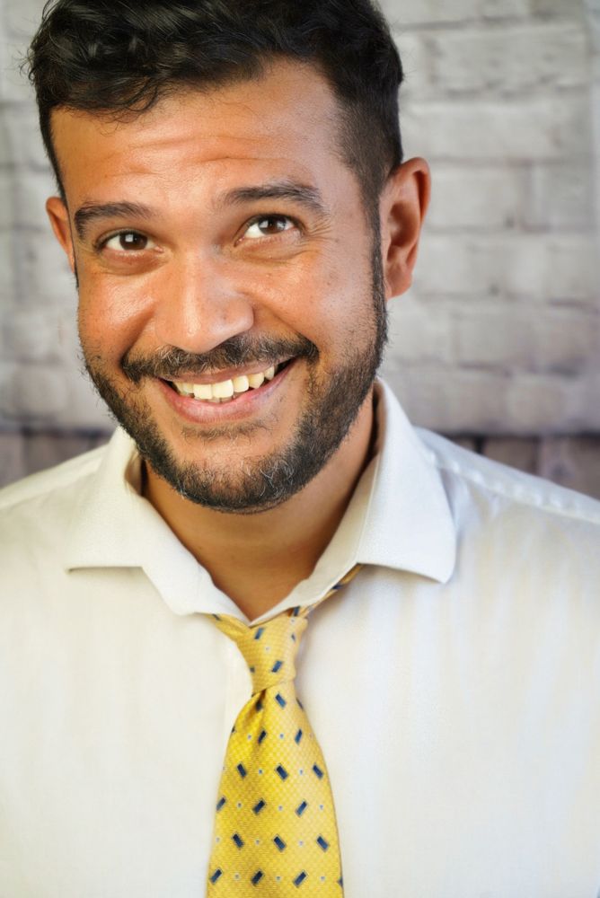 Jason grinning in a white shirt and yellow tie